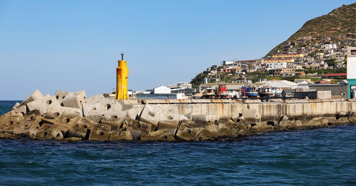 Mohale's Hoek Travel Guide: Planning Tips, Costs and Things to Do Vibrant harbor scene in Hout Bay, Cape Town, showcasing colorful buildings and ocean waves.