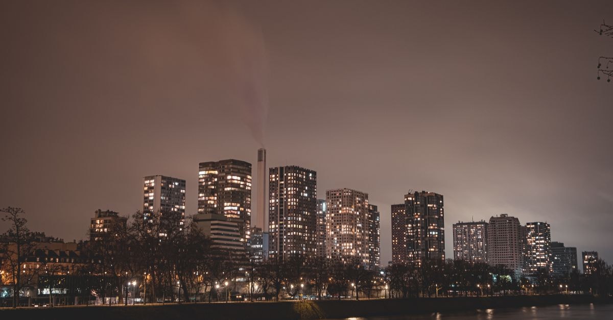 Captivating nighttime view of Paris skyline with illuminated skyscrapers along the river.