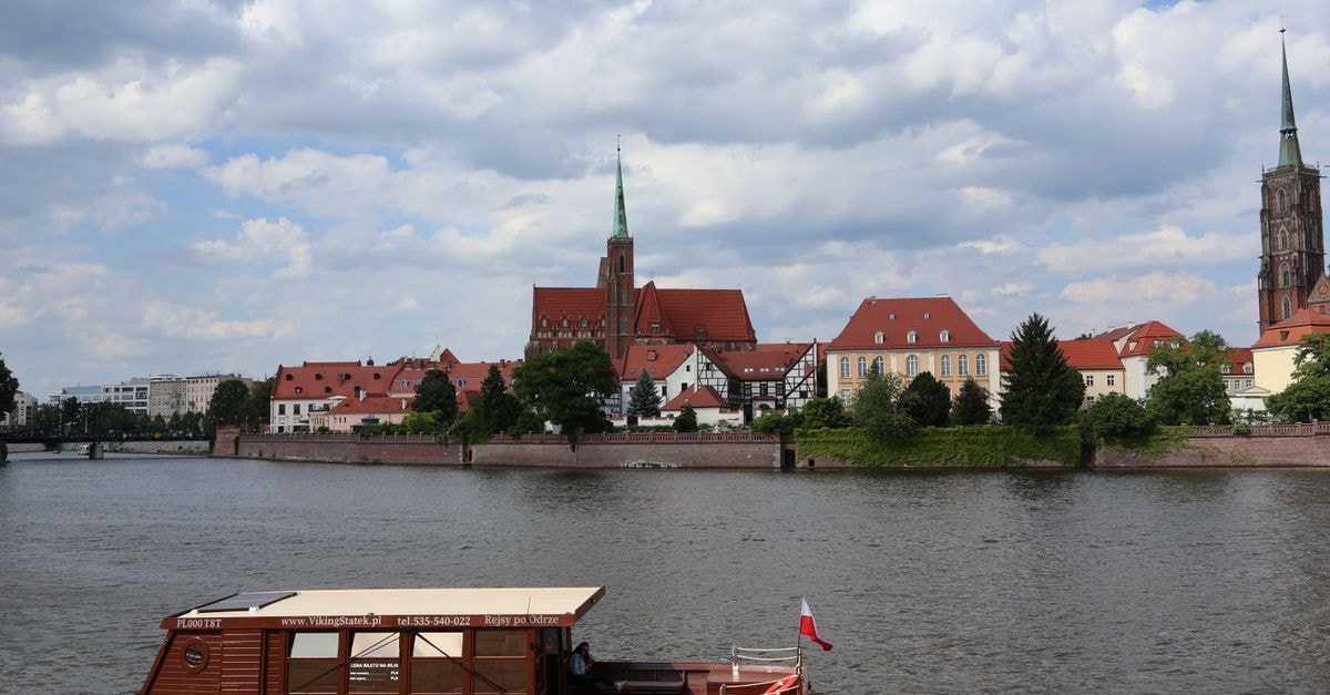 Wroclaw Travel Guide: Planning Tips, Costs and Things to Do Serene view of Ostrow Tumski with a boat on the Odra River in Wrocław, Poland.