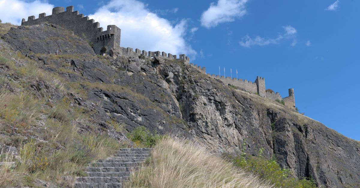 Impressive stone fortress atop a rocky hill in Stirling, Switzerland under a bright blue sky.