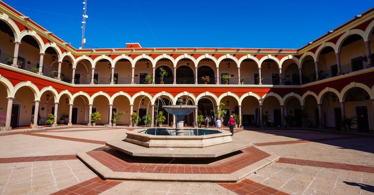 Hotel Colón in Mérida: Colonial Architecture Near Plaza Mayor Arched colonial courtyard with central fountain under bright blue sky in Topolobampo, Sinaloa, Mexico.