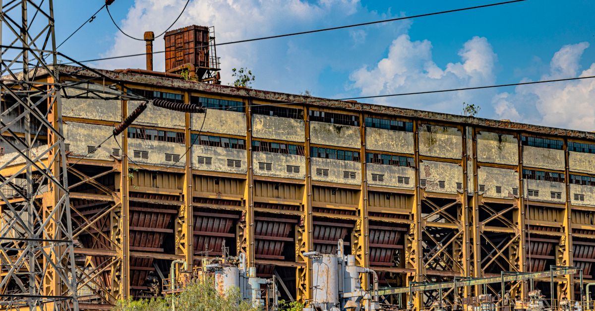 A dramatic view of an abandoned industrial structure in Delhi, India under a vibrant sky.
