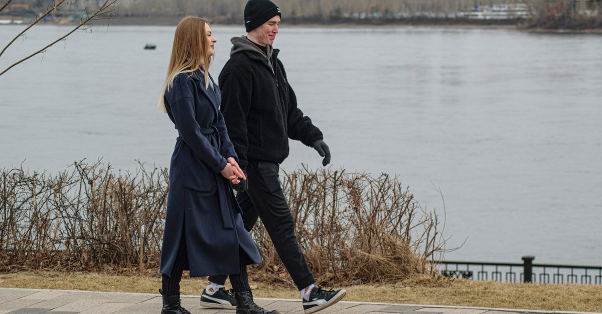 Walking into Krasnoyarsk: a slow travel guide to Siberia's river city A young couple enjoys a winter walk along a riverside path in an urban park setting.