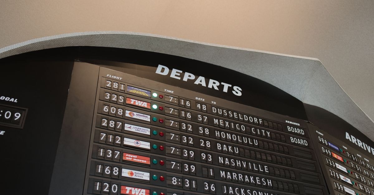 Close-up of airport departure board displaying flight details at JFK Airport, New York.