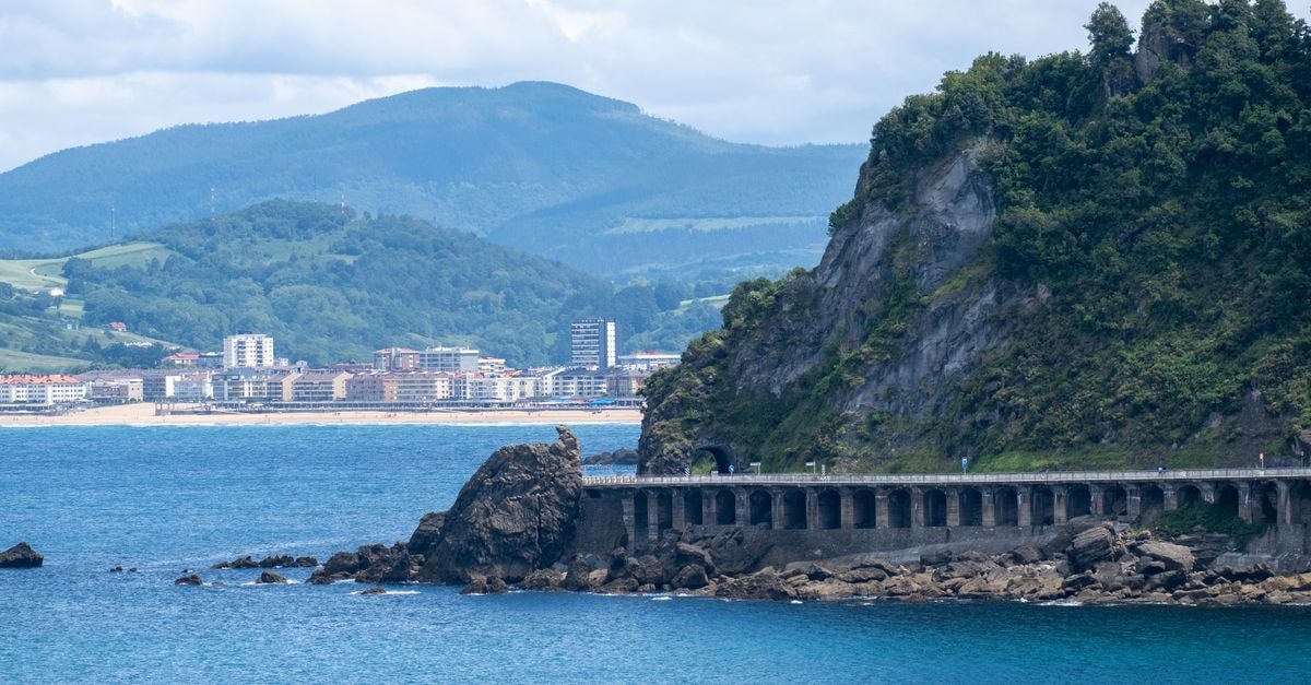 View of the coastline and cityscape in San Sebastián, Spain with rocky cliffs.
