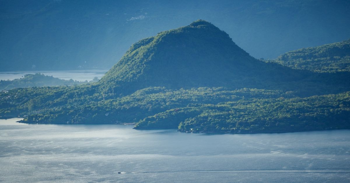 A picturesque view of Cerro de Oro surrounded by lush greenery and tranquil water in Sololá, Guatemala.
