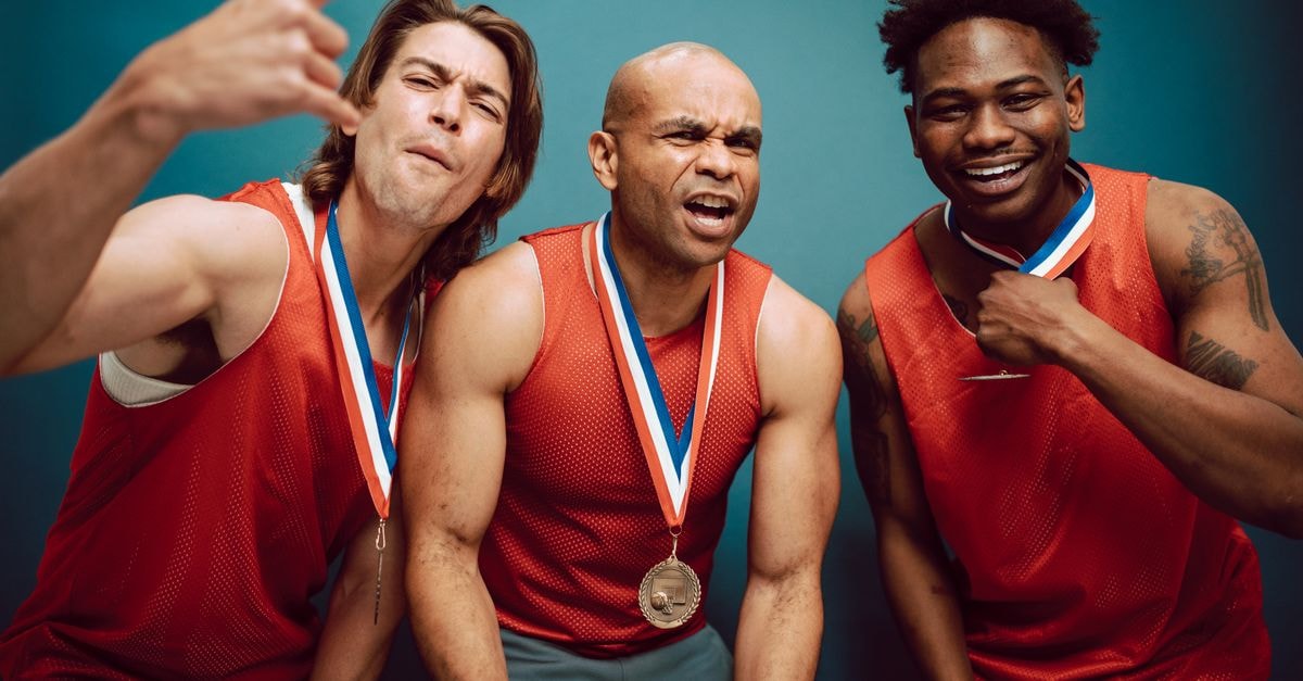 Reeve defends trans athletes as WNBA controversy builds; Durant compares LeBron's 76ers to champion Warriors Three diverse athletes celebrating victory, wearing medals and red jerseys against a blue background.