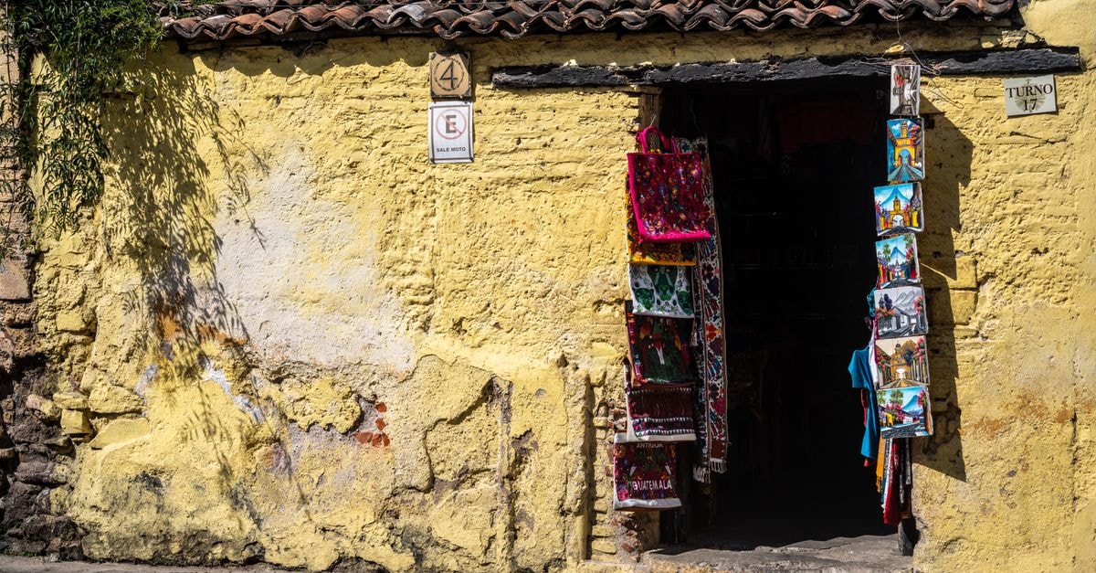 Rustic market stall with vibrant textiles on a sunny cobblestone street.