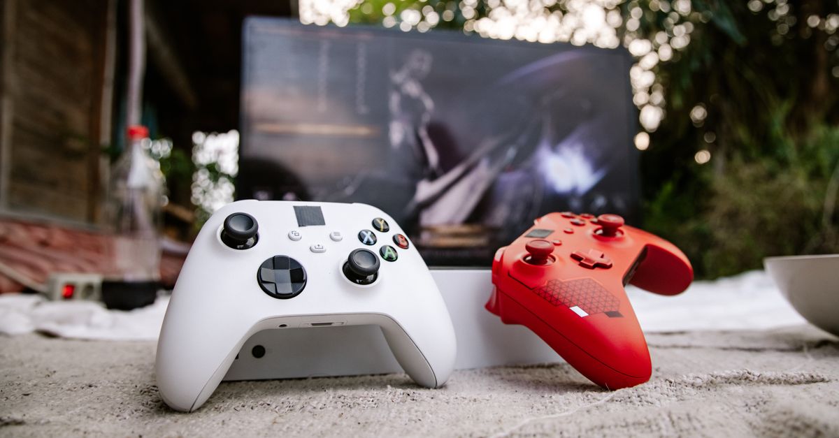 Microsoft Tests Free Ad-Supported Xbox Cloud Gaming as Xbox Live Outage Disrupts Halo Launch White and red Xbox wireless controllers set outdoors. A computer screen is blurred in the background.