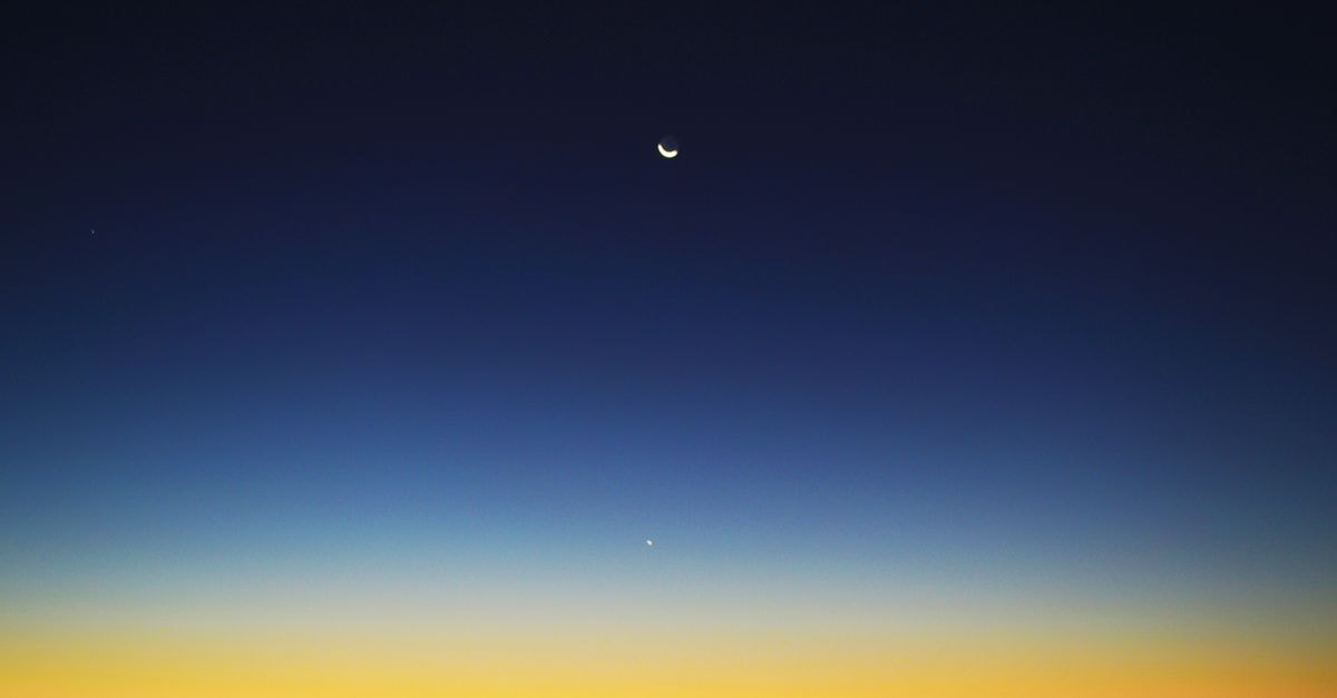 Crescent moon and planet visible in a colorful twilight sky over Mahajanga, Madagascar.