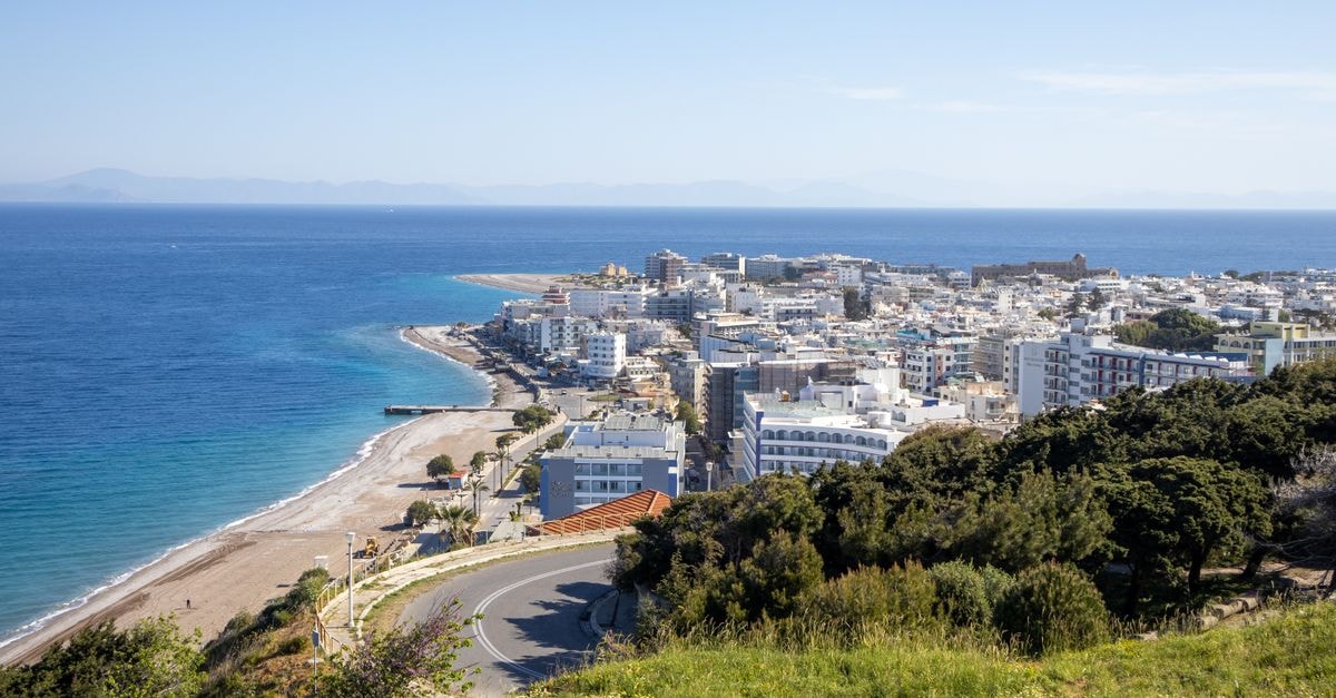 Larissa Travel Guide: Things to Do in Greece's Thessalian Heart Aerial view of a coastal city with beaches, green hills, and a vast blue sea under a clear sky.