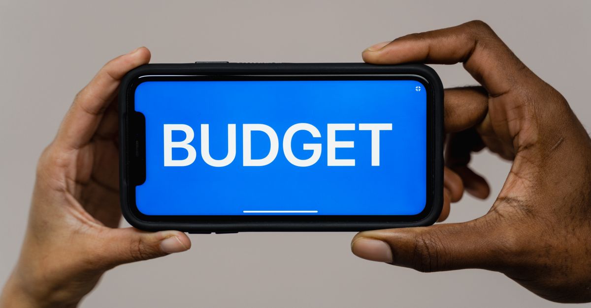 Lava enters budget market via Flipkart as Honor, Google and Counterpoint reshape smartphone strategies Two hands hold a smartphone displaying the word 'budget' on a blue screen, symbolizing financial planning.