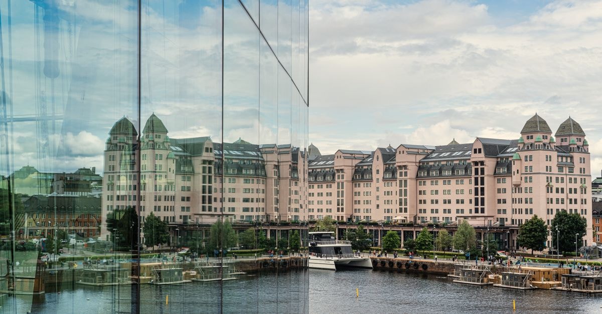 Modern glass building reflecting historic waterfront architecture in Oslo, Norway.