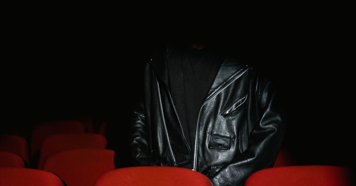 蜘蛛人穩坐中國票房冠軍,諾蘭《奧德賽》IMAX 預映來勢洶洶 身著黑色皮夾克的男子坐在昏暗電影院中的紅色座椅之間。