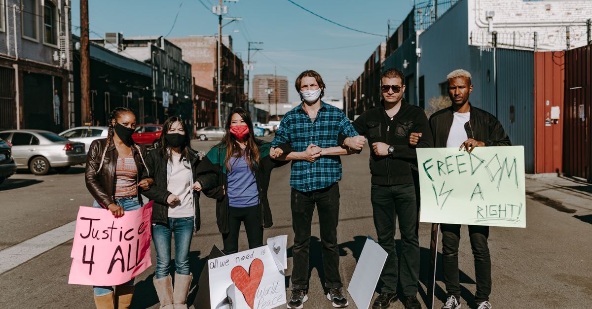 Kyle Sandilands Steps Down from Australian Idol Ahead of Activist Campaign A diverse group of people holding signs for justice and freedom during a daytime protest.