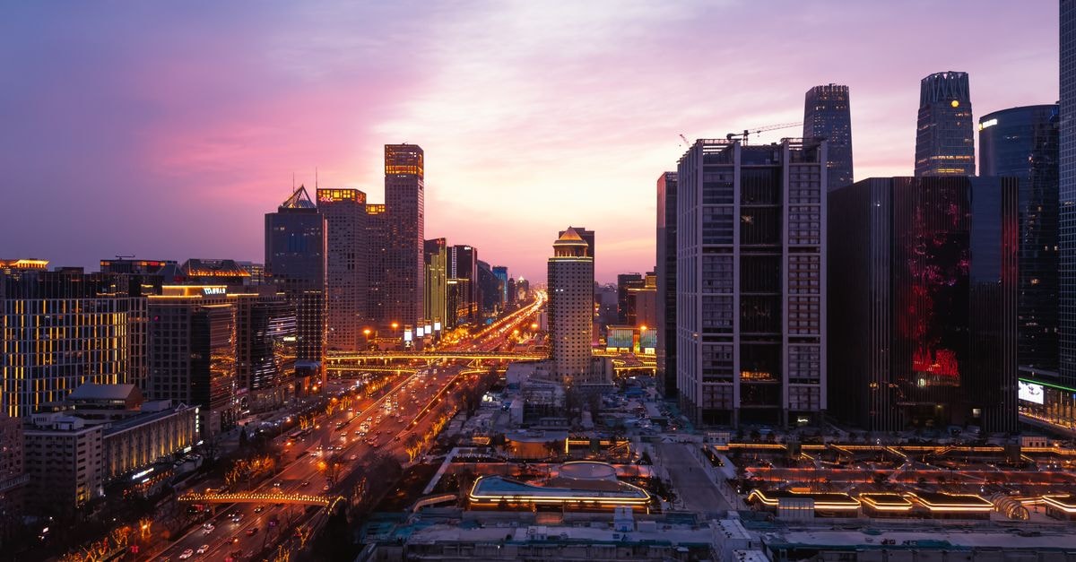 Kelly's Courtyard, Beijing — A Hutong Inn Steps from Xisi Station A breathtaking panoramic view of Beijing's urban skyline at dusk with vibrant city lights and a colorful sky.
