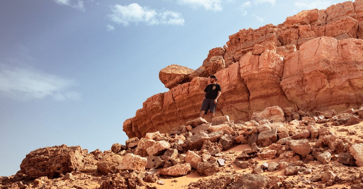 Adrar Travel Guide: Desert Calm, Cooler Months, and How to Plan Smart A man stands amidst rocky formations and desert landscape in Timokten, Adrar Province, Algeria.