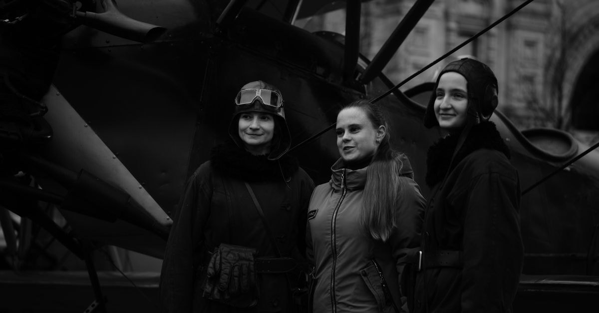 Aviator Hotel in Nizhnevartovsk: A Stay on Aviators Street Three women in vintage aviator attire pose in front of a classic aircraft, capturing a nostalgic aviation theme.