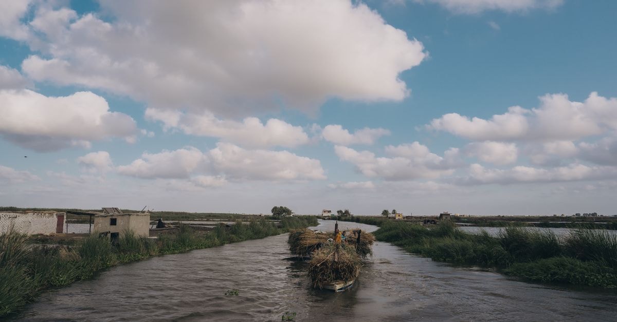Serene rural canal view with clouds and boat in Kafr El-Shaikh, Egypt.