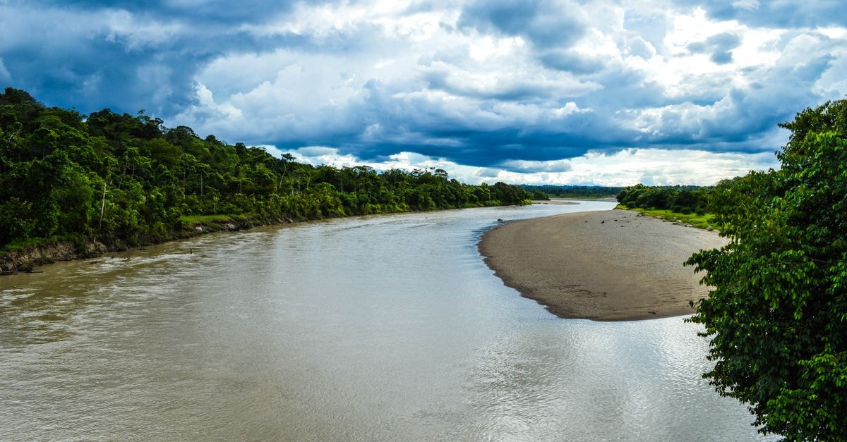 Cobija Travel Guide: Gateway to the Bolivian Amazon A vibrant landscape of a river winding through lush greenery under dramatic skies in Puerto Nuevo, Chocó, Colombia.