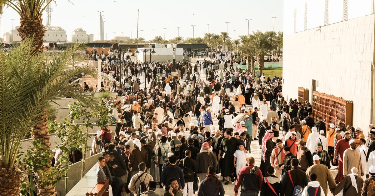A bustling outdoor scene in Saudi Arabia with diverse people gathered outdoors.
