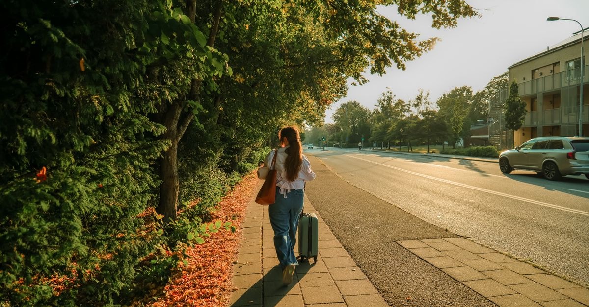 Hotel Bishops Arms, Lund — A Cozy Stay 300 Meters from the Station A woman walking on a Lund street with a suitcase during a picturesque sunset.