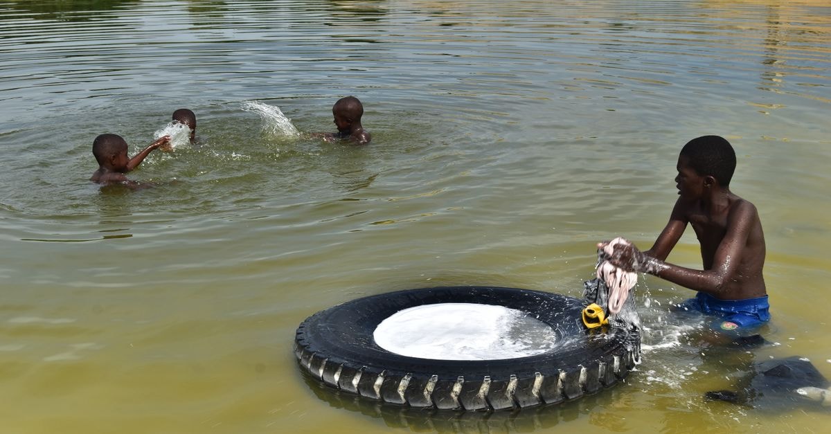 Slow Mornings on the Congo: A Kisangani Travel Guide Boys washing clothes in a lake using a tire as a basin in the Republic of Congo.