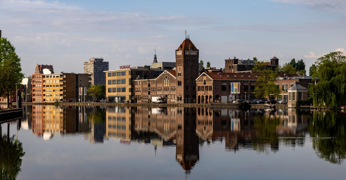 B&B Stoet & Berre in Assen: A Private Forest-Edge Apartment Scenic view of historic buildings reflecting in a canal in Zaandam, Netherlands, on a sunny day.
