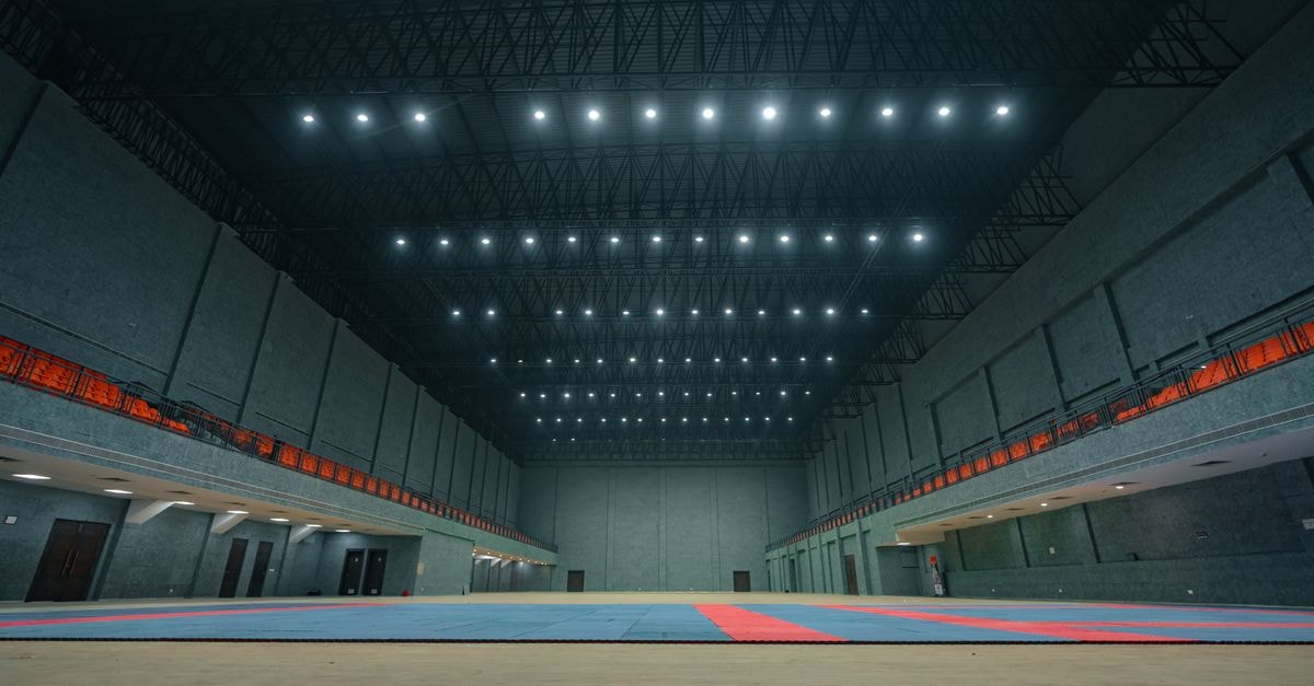 Treesa and Gayatri reach World Championships semifinals, ending India's 15-year medal wait Spacious indoor sports hall with bright ceiling lights and empty flooring in Surat, India.