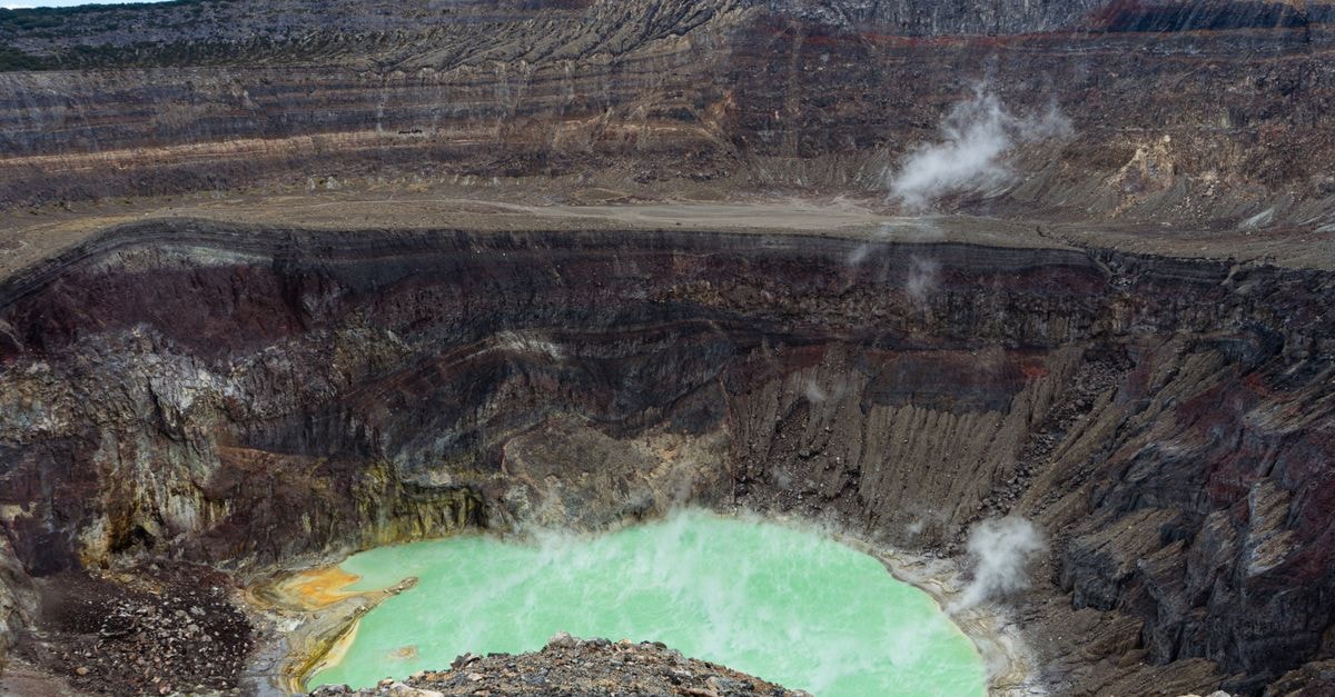 Masaya Travel Guide: Planning Tips, Costs and Things to Do A breathtaking view of an active volcano crater with a vibrant sulfuric lake emitting steam under a clear sky.