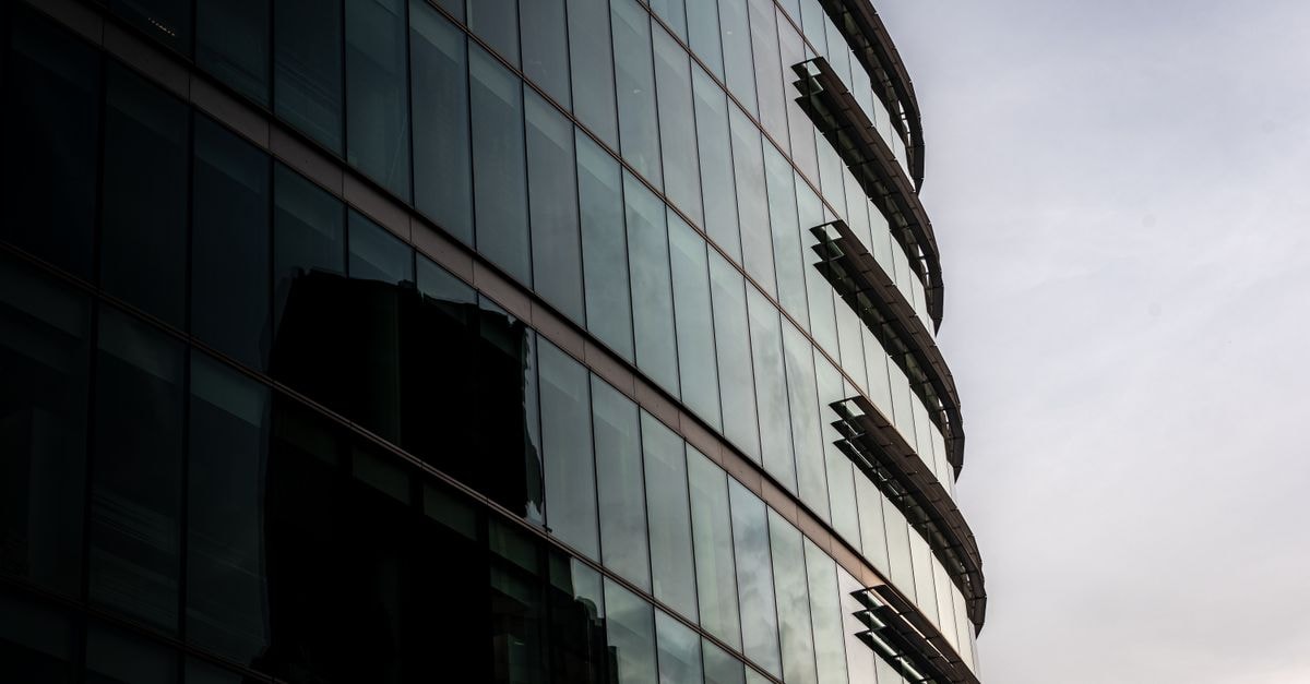 Contemporary glass office building reflecting cityscape in London, UK.