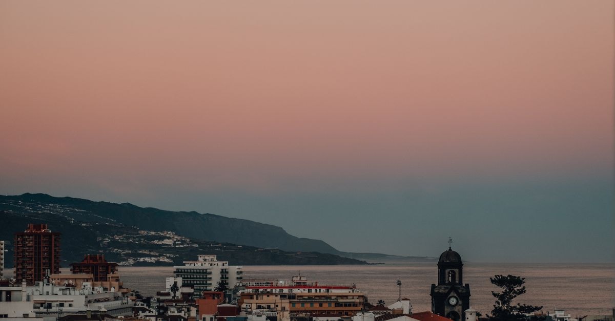 A serene twilight view of a coastal city with an ocean backdrop and pastel skies.
