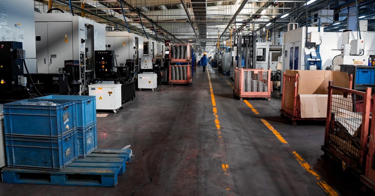 PepsiCo to end manufacturing operations at Maryland bottling plant, cutting 143 jobs Vast industrial factory floor with machinery, crates, and structured workstations.