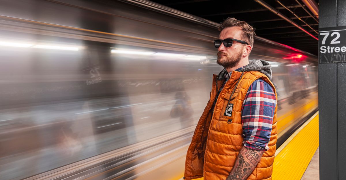 New York Bans Smart Glasses From Courthouses as Platforms and Makers Respond Casual man standing at 72nd Street subway station, New York City, looking at a passing train.