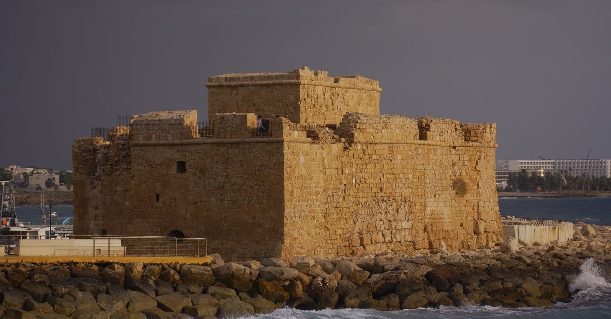 Paphos Travel Guide: Beaches and Ancient Heritage Paphos Castle in Cyprus, a medieval stone fortress by the sea, under dramatic skies.