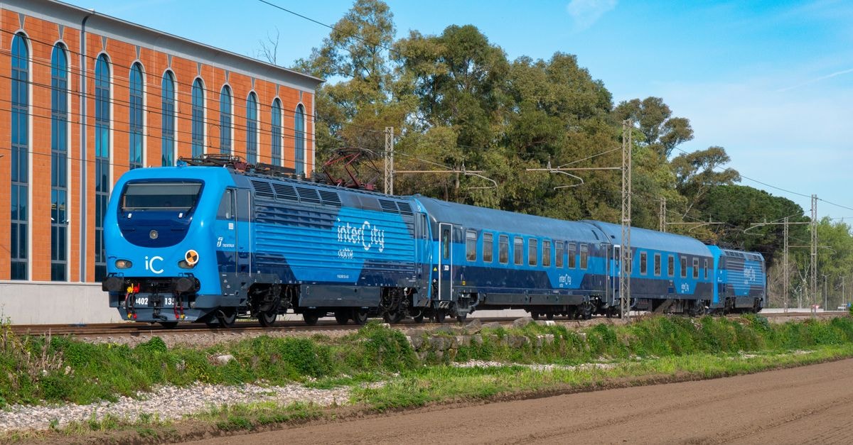 Intercity Anápolis in Anápolis: A Practical Base Near the Agro-Industrial District A sleek blue intercity train travels past a historical building in Caserta, Italy, during the day.