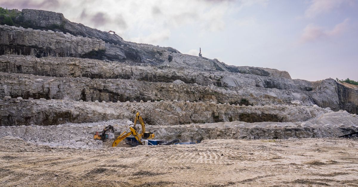 UK National Wealth Fund commits up to £71 million to restart Tungsten West's Hemerdon mine A quarry with excavators working on rocky terrain under a cloudy sky.