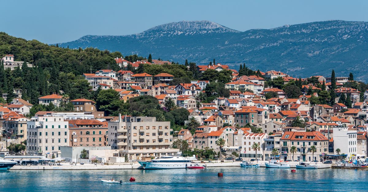Split, Croatia Travel Guide for July 2026: Festivals, Beaches, and Old-Town Heat A beautiful coastal town with red-roofed buildings and mountains in the background.