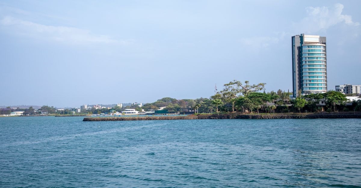 A modern cityscape featuring a tall building by the coastal waterfront under a clear sky.
