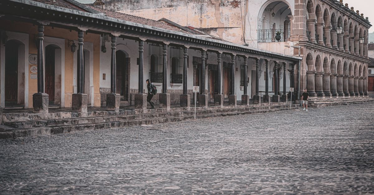 Elegant colonial buildings with stone archways and cobblestone streets in Antigua Guatemala.