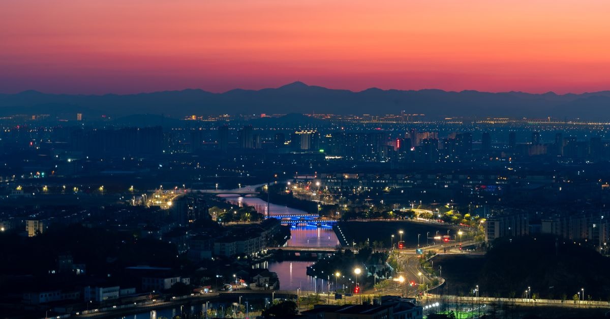 Yan'an in Shaanxi: Where Revolutionary-Era History Lives in Stone A vibrant cityscape at twilight showcasing a glowing skyline and a colorful sunset horizon.
