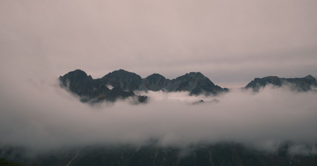 Nagano Travel Guide: Quiet Rhythms and Mountain Calm Dramatic misty view of mountain peaks in Azumino, Nagano, Japan, at twilight.