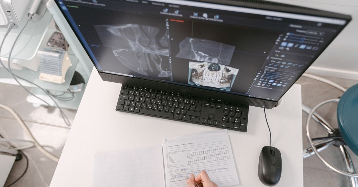 CareCloud Confirms 3.7 Million Patients Affected in March Data Breach Radiologist analyzing X-ray scans on a computer monitor while taking notes. Medical documents visible.