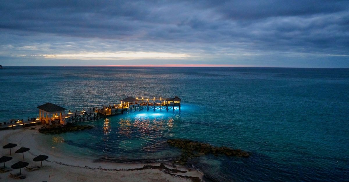 A tranquil seascape at twilight with a pier illuminated over Nassau's blue waters.