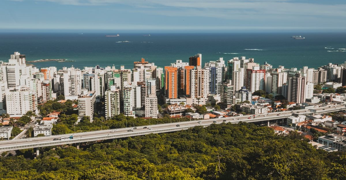 A vibrant city skyline with buildings by the ocean under a clear blue sky.