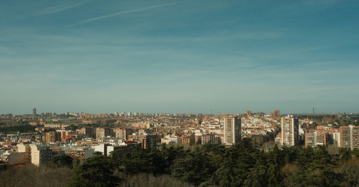 A wide view of Madrid's skyline under a clear blue sky, surrounded by urban architecture and greenery.