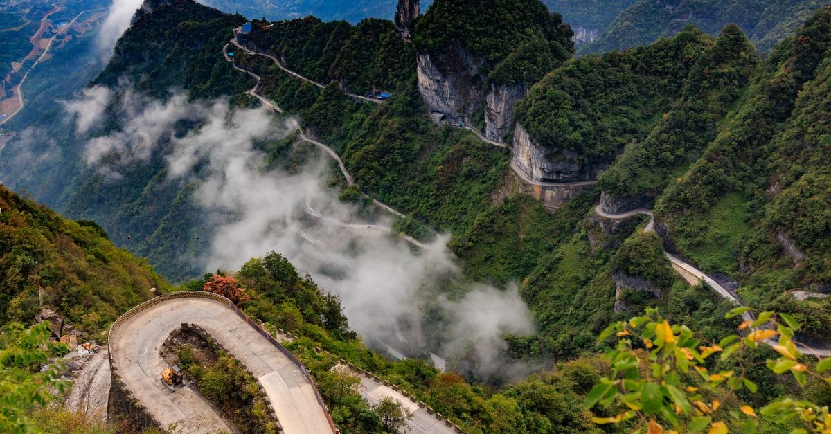 Nanping Travel Guide: Mountains, Mist, and Wuyi Mountain Breathtaking view of a winding road in Tianmen Mountain with lush green landscape and misty clouds.