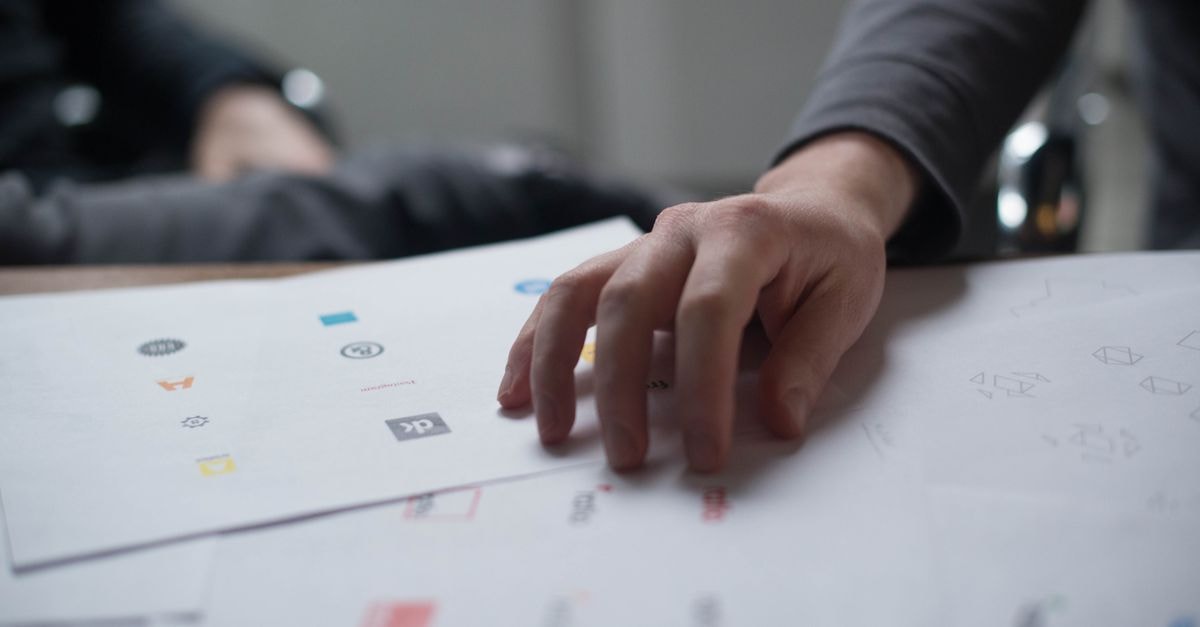 New Concept Energy: A Cash-Burn Real Estate Shell, Not an Oil & Gas Producer A close-up shot of a hand reviewing various logo designs on paper, ideal for business concepts.