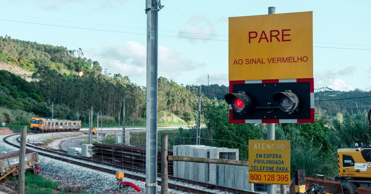 A Quiet Borderland Stop: Comendador Travel Guide Railway crossing with a stop sign 'PARE', train approaching in scenic landscape.