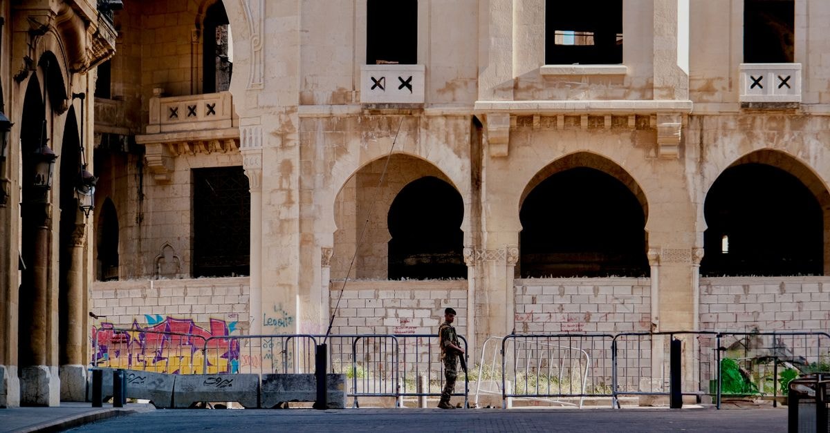 Hilton Beirut Downtown, Beirut — A New Door Opens in the Central District A soldier stands in front of a historical building in Beirut, Lebanon, highlighting urban architecture.